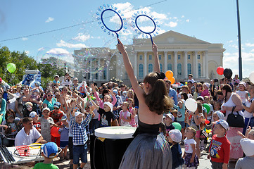 Image showing Happy children catch soap bubbles on the street in the city of T