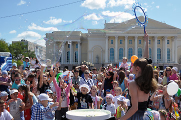 Image showing Happy children catch soap bubbles on the street in the city of T