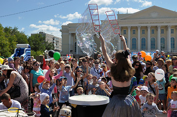 Image showing Happy children catch soap bubbles on the street in the city of T