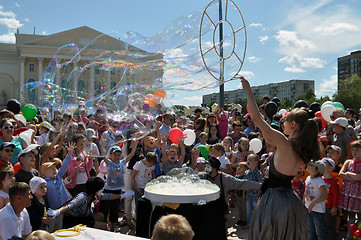 Image showing Happy children catch soap bubbles on the street in the city of T
