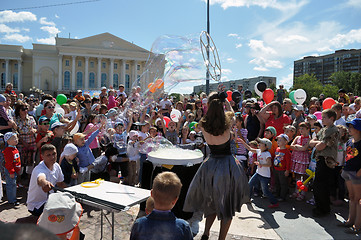 Image showing Happy children catch soap bubbles on the street in the city of T