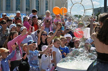 Image showing Happy children catch soap bubbles on the street in the city of T