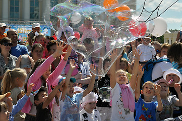 Image showing Happy children catch soap bubbles on the street in the city of T