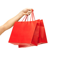 Image showing close up of hand holding red shopping bags