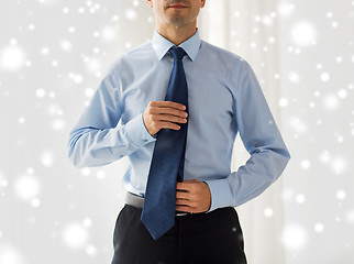 Image showing close up of man in shirt adjusting tie on neck