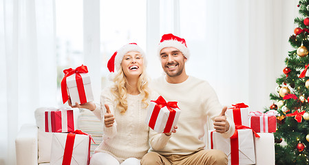 Image showing happy couple with christmas gifts and thumbs up