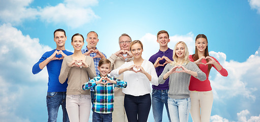 Image showing people showing heart hand sign over sky and clouds
