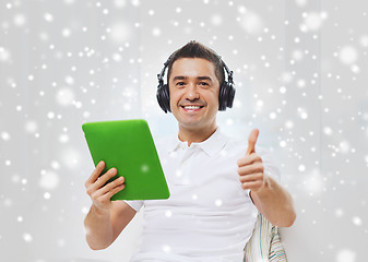 Image showing smiling man with tablet pc and headphones at home