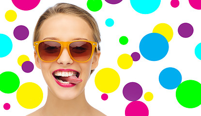 Image showing happy young woman in sunglasses showing tongue