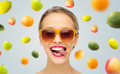 Image showing happy young woman in sunglasses showing tongue