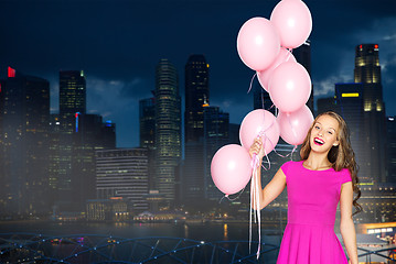 Image showing happy young woman with balloons over night city