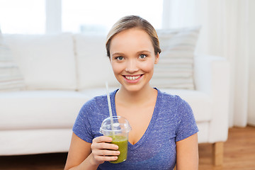 Image showing happy woman with smoothie sitting on mat at home