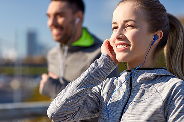 Image showing happy couple with earphones running in city