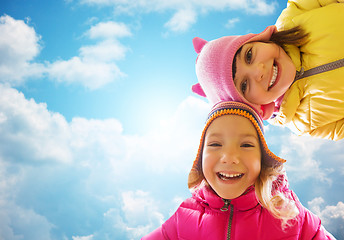 Image showing happy little girls faces over blue sky