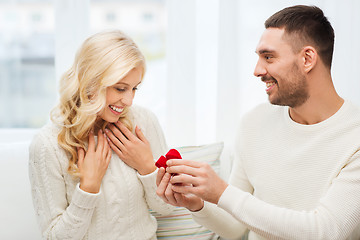 Image showing happy man giving engagement ring to woman at home