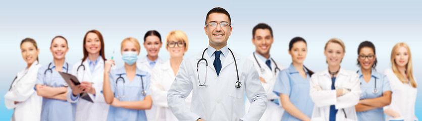 Image showing group of smiling doctors with clipboard over gray