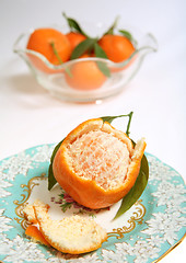 Image showing Half peeled clementine on plate