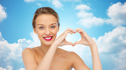 Image showing smiling young woman showing heart shape hand sign