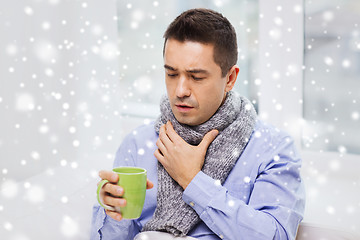 Image showing ill man with flu drinking tea and coughing at home