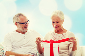 Image showing happy senior couple with gift box at home