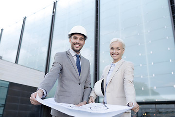 Image showing smiling businessmen with blueprint and helmets