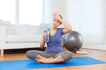 Image showing tired woman drinking water after workout at home