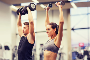 Image showing smiling man and woman with dumbbells in gym