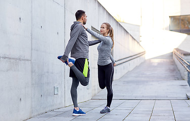 Image showing smiling couple stretching leg outdoors