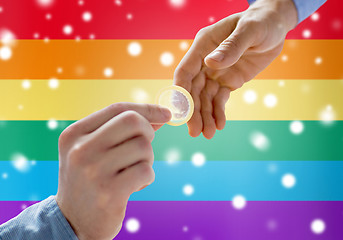 Image showing close up of male gay couple hands giving condom