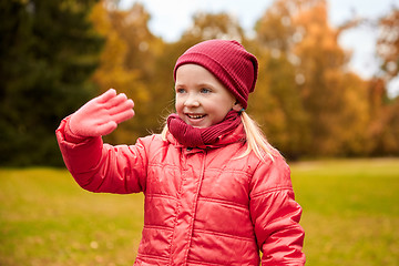 Image showing happy little girl waving hand in autumn park