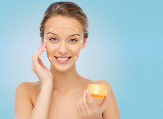 Image showing happy young woman applying cream to her face