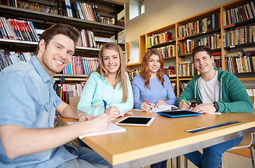 Image showing happy students writing to notebooks in library