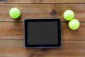 Image showing close up of tennis balls and tablet pc on wood