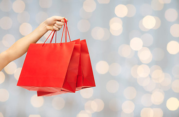 Image showing close up of hand holding red shopping bags