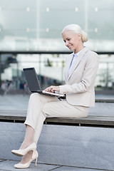 Image showing smiling businesswoman working with laptop outdoors