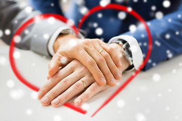 Image showing close up of gay couple hands with wedding rings on