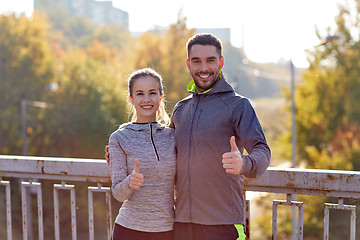 Image showing smiling couple showing thumbs up outdoors