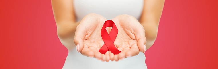 Image showing close up of hands with red AIDS awareness ribbon