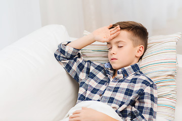 Image showing ill boy lying in bed and suffering from headache