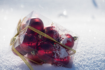 Image showing christmas balls in box on fresh  snow