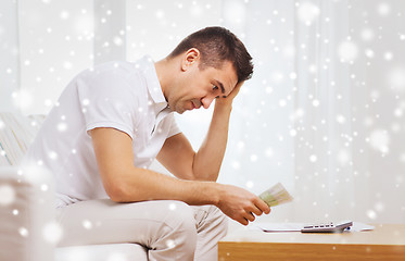 Image showing man with money and calculator at home