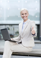 Image showing smiling businesswoman working with laptop outdoors