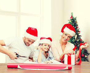Image showing happy family in santa helper hats packing gift