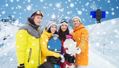 Image showing happy friends with snowboards and smartphone