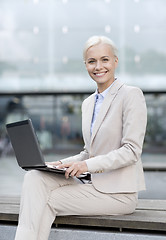 Image showing smiling businesswoman working with laptop outdoors