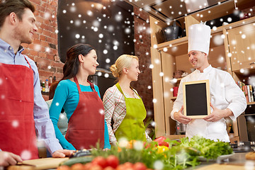 Image showing happy friends and chef cook with menu in kitchen