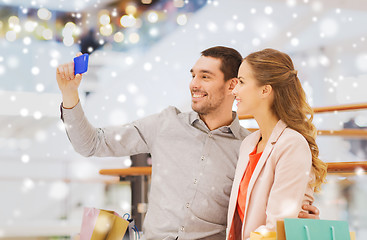 Image showing happy couple with smartphone taking selfie in mall