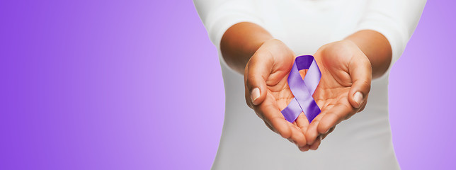 Image showing close up of hands holding purple awareness ribbon