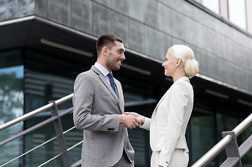 Image showing smiling businessmen shaking hands on street