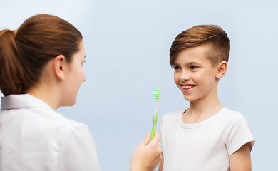 Image showing doctor with toothbrush and happy boy in clinic